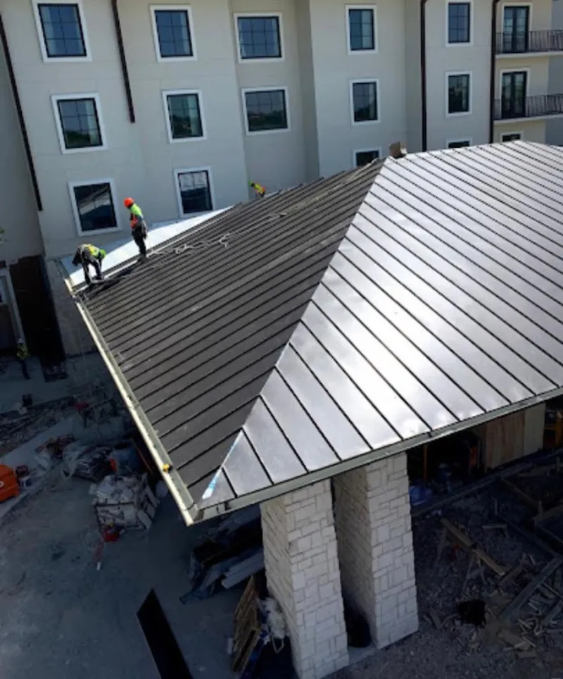 Crew installing standing seam metal roof panels on a commercial project in International Falls